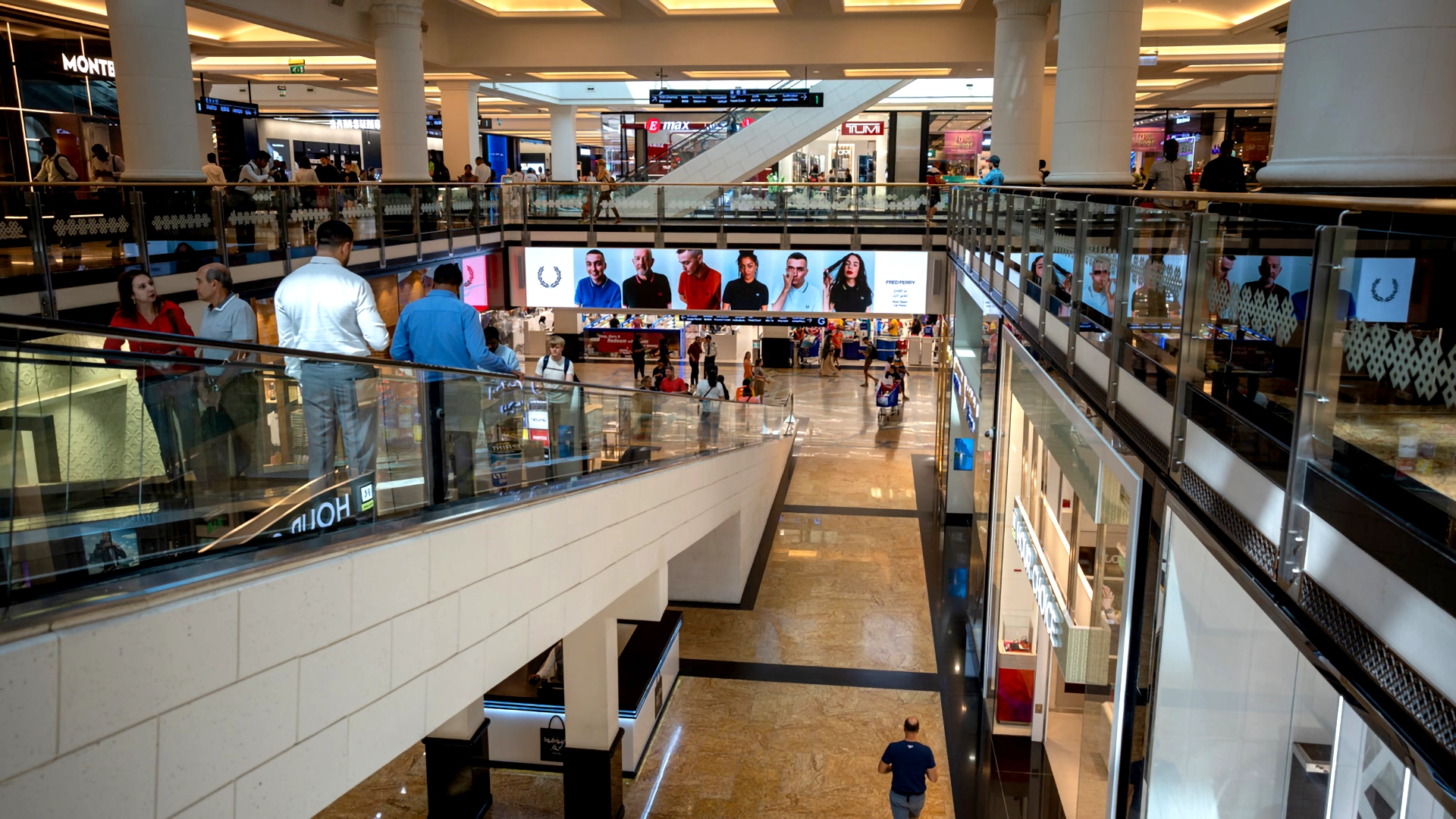 Shoppers captivated by an advert for Fred Pery placed on an escalator in The Mall of the Emirates