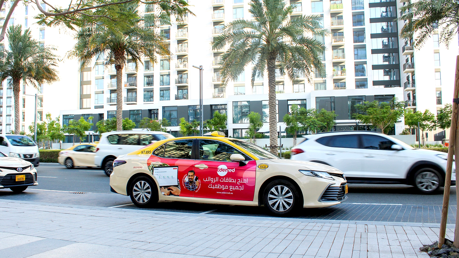 An advert for Edenred on the side of a taxi as it travels along a busy road in Duabi