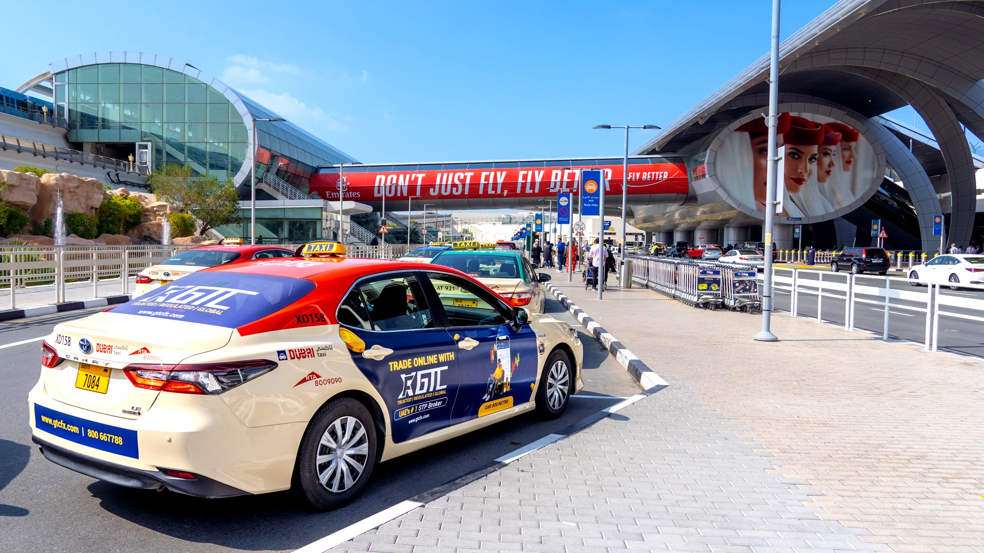 A taxi with bold advertising for GTC arrives at Dubai International Airport