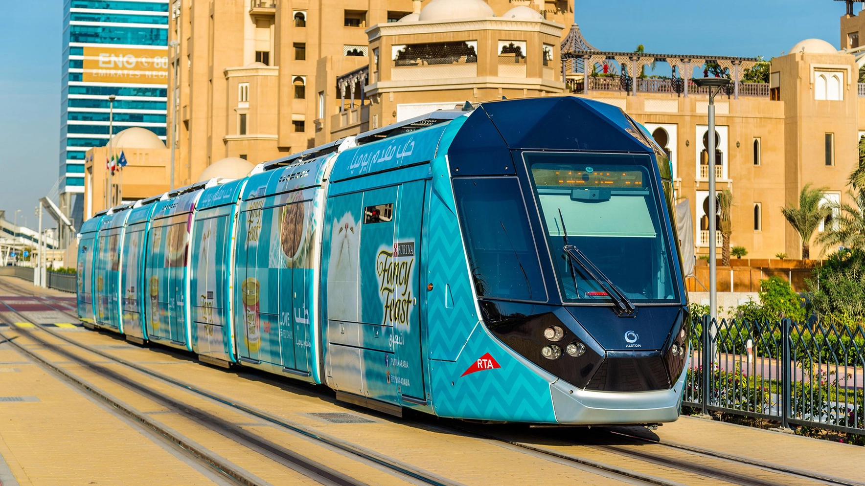 A tram branded for Fancy Feast cat food passes by the Dubai Marina skyline