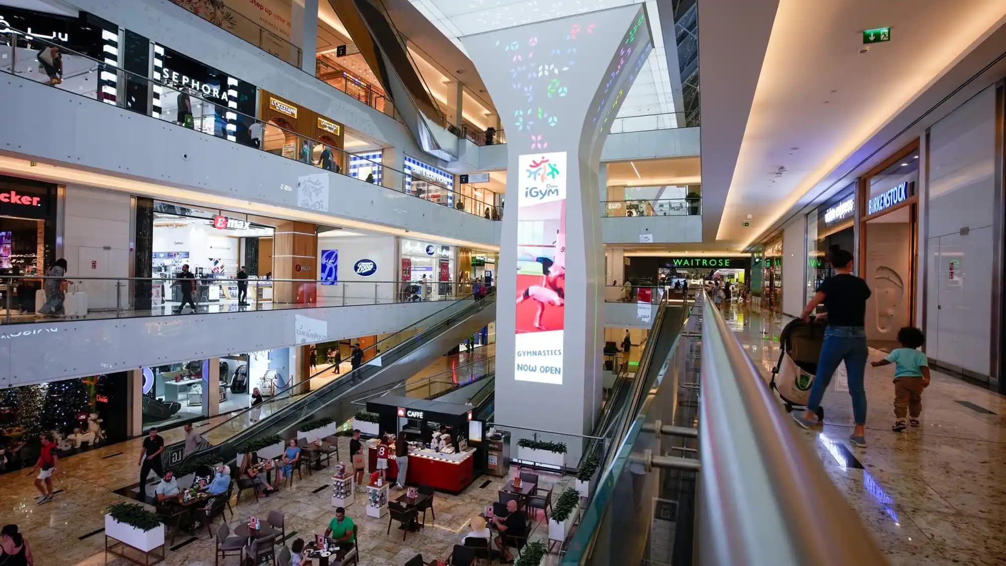 Shoppers captivated by an advert for Fred Pery placed on an escalator in The Mall of the Emirates