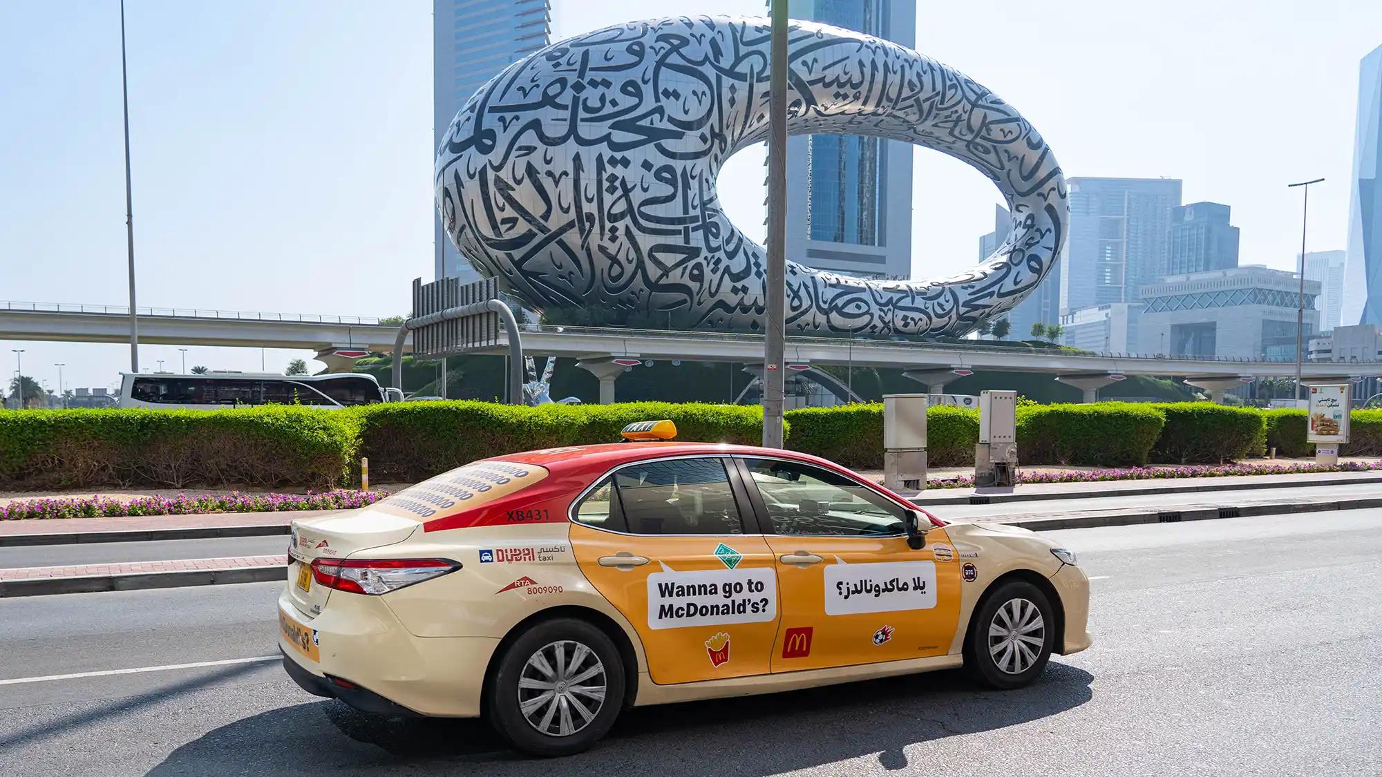 An advert for Edenred on the side of a taxi as it travels along a busy road in Duabi